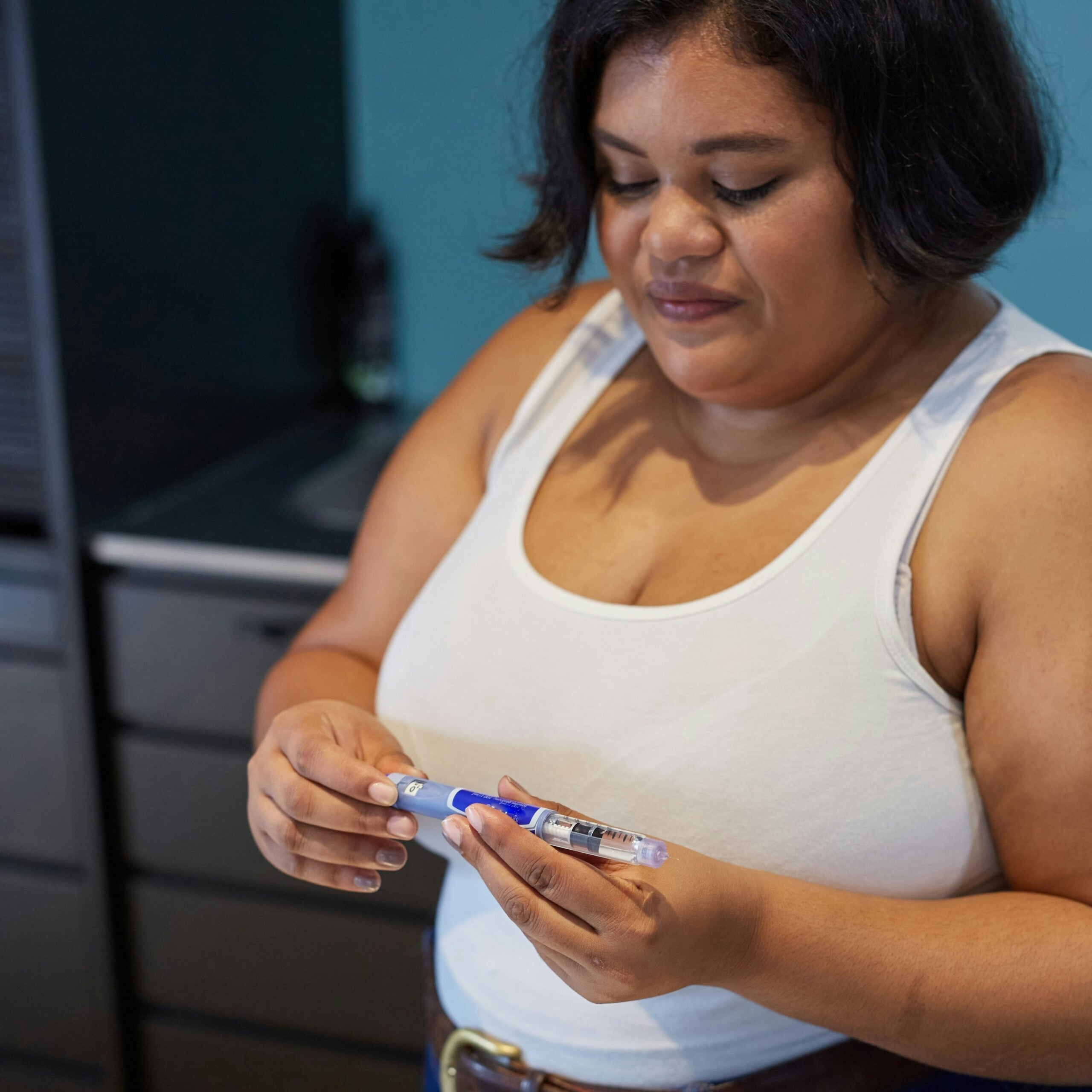 Woman holding a weight loss injection pen.